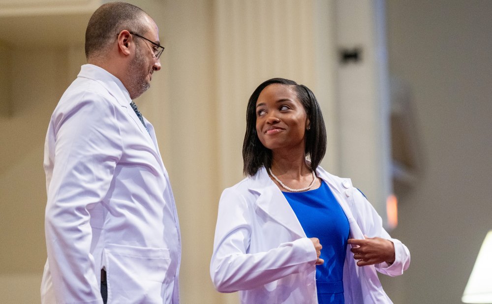 BUCOM Student Receiving White Coat Looking Back at Professor
