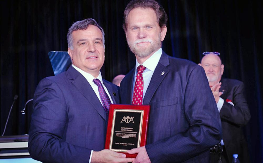 Joseph Giaimo, DO, 125th President of the AOA, presents the Distinguished Service Award to Dr. Bell.