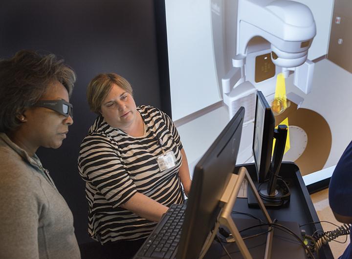 Student and Teacher discussing the virtual technology used in Radiation Therapy