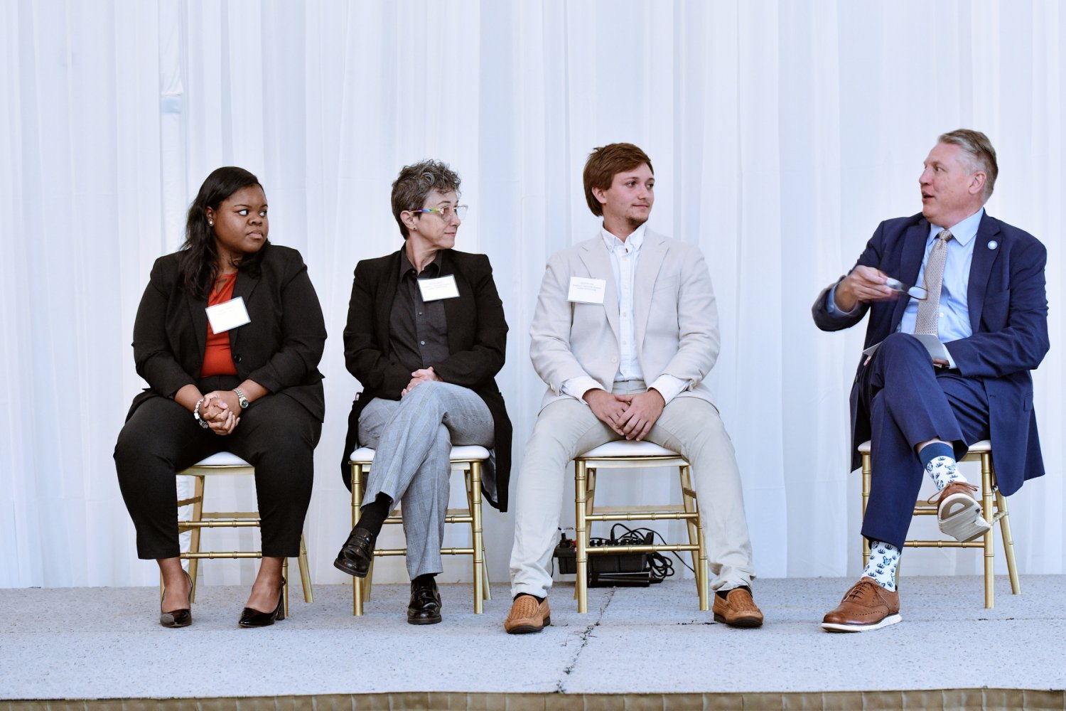 Four panelists sit on stage in discussion during a university event.