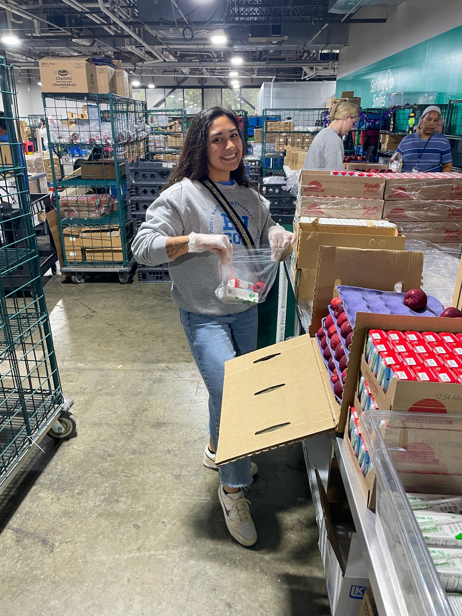 one student posing next to boxes while packaging items 