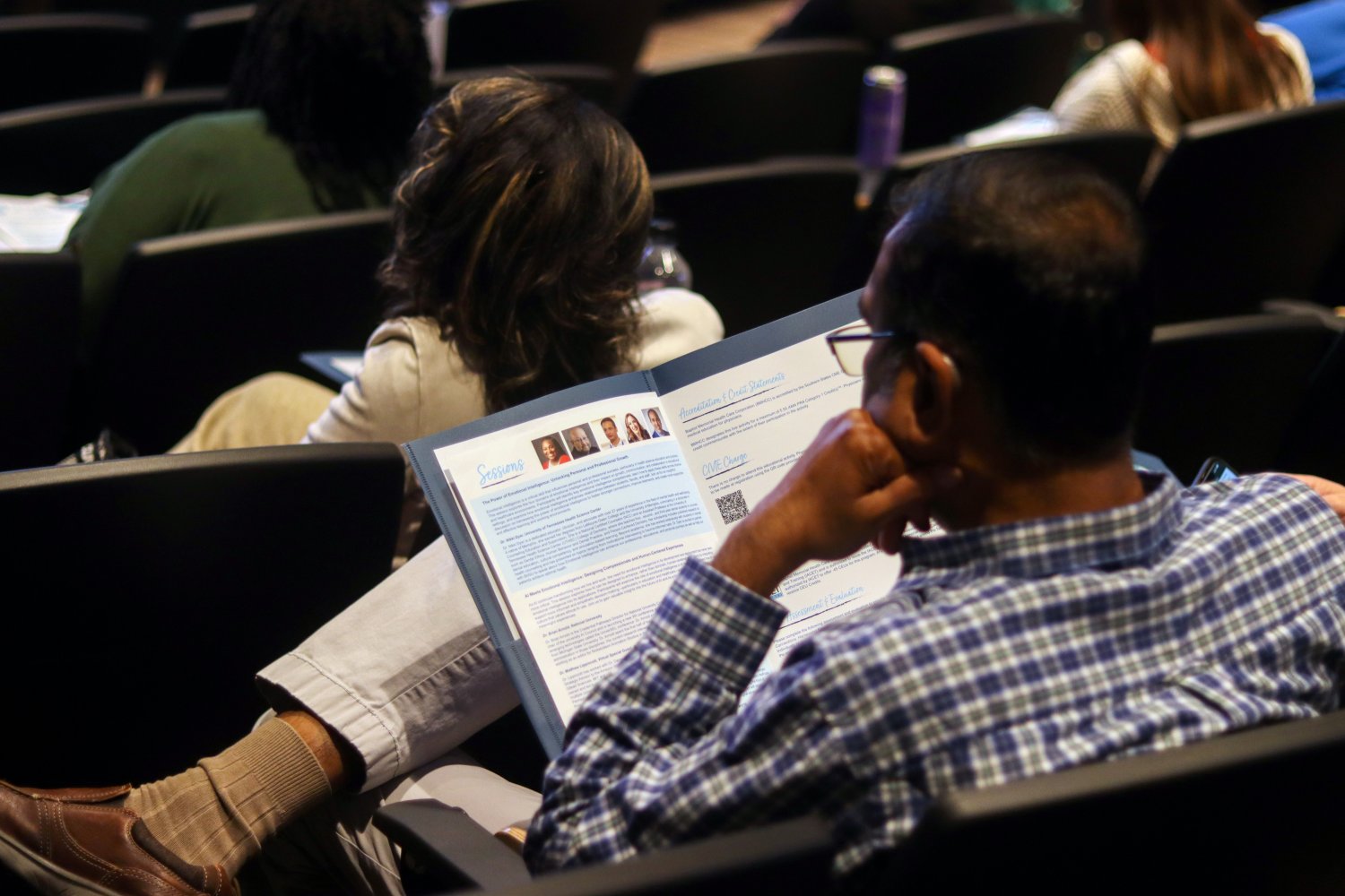 photo of a person sitting crosslegged looking at a flyer 