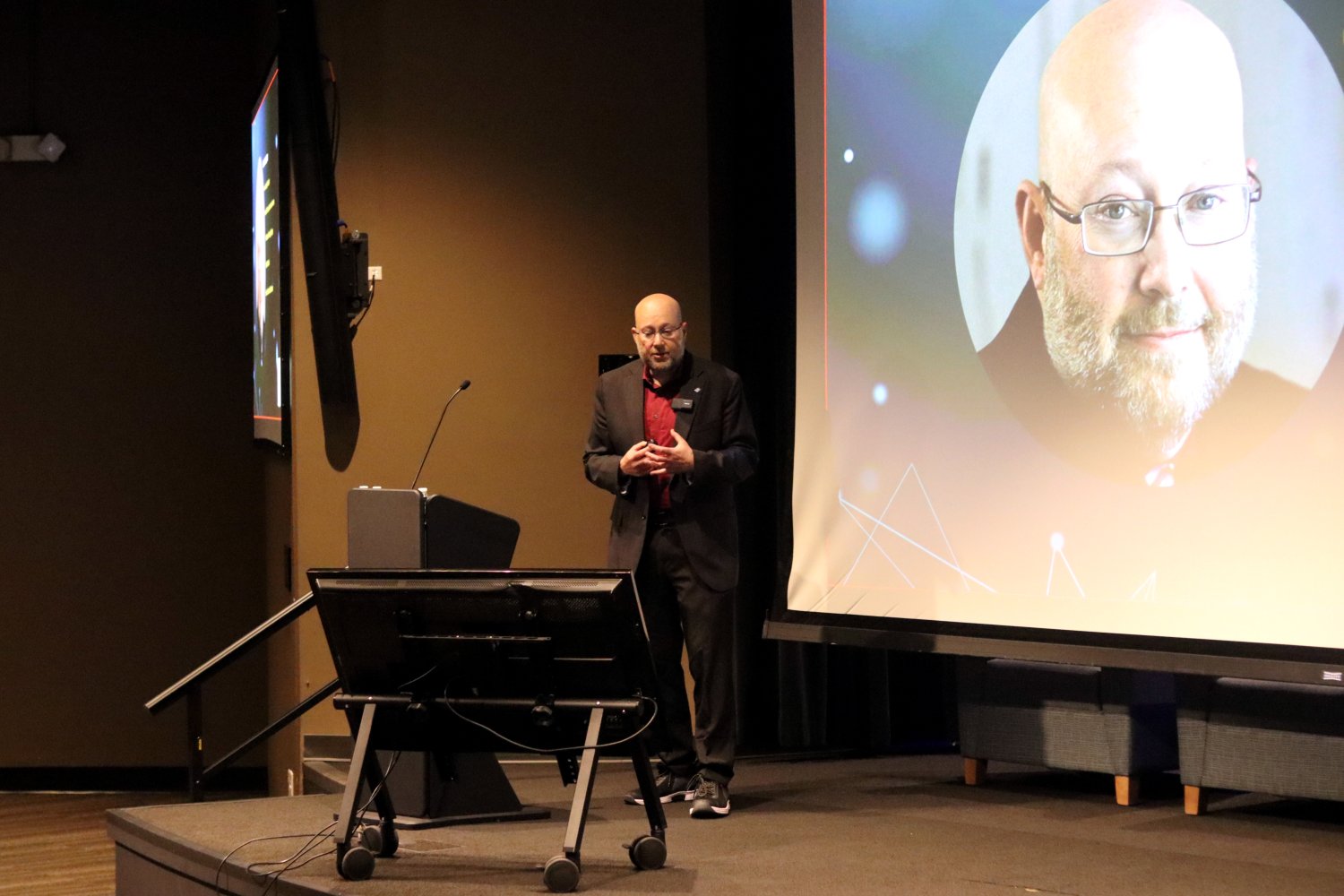 one person on the stage with an image of him on a projection screen behind him