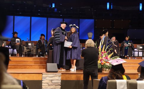 One person smiling with Hampton in a cap and gown