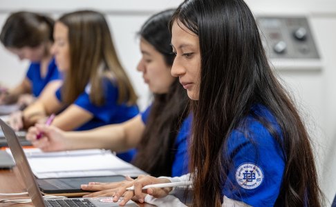 Students in blue scrubs work on laptops during a classroom session at Baptist Health Sciences University.