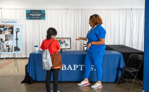 two people in an image one in blue scrubs and the other in a red shirt and black pants 