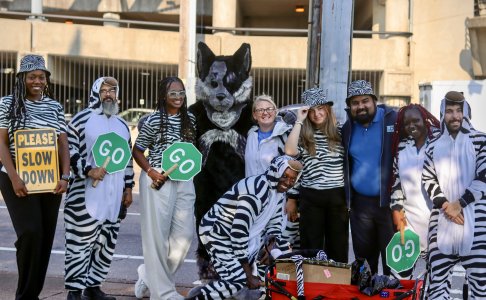 Group photo of everyone with zebras and Hartley the mascot 
